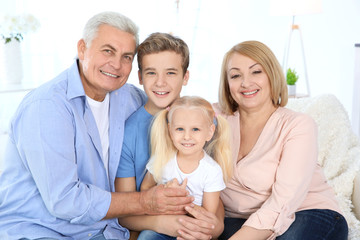 Cute children with grandparents sitting on sofa in living room