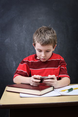 School boy playing a video game while at his desk