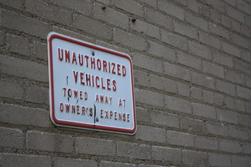 Fototapeta na wymiar Unauthorized Vehicles Towed Away At Owner's Expense porcelain sign.