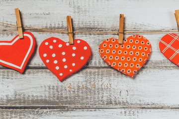 handmade toy hearts hanging from a rope on a white wooden background