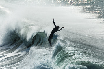 Surfer flails in the air after falling off his board on a wave