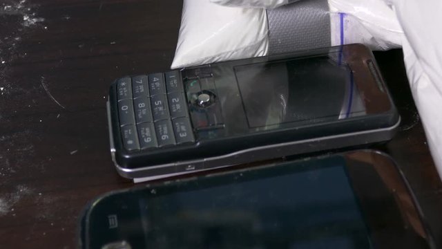 Seized drugs, money, gun, and burner phones on table