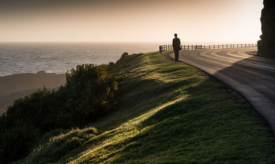 Lone girl walks along coast clifftop road