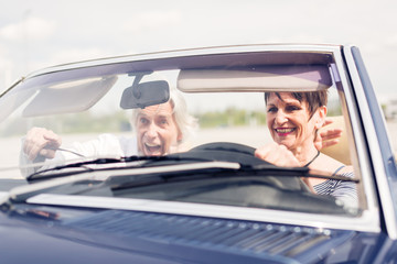 Senior Couple Driving A Convertible Classic Car