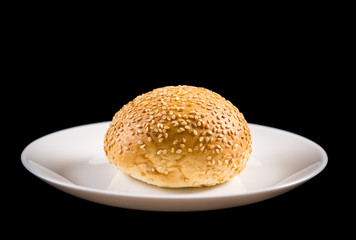 Bun with sesame seeds on white dish