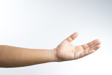 Hand with yellow pill in palm