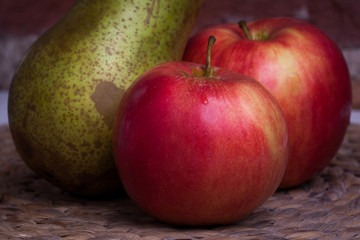 Green pear and red apple on a background wall.