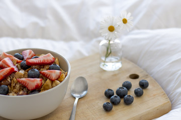 Breakfast on the bed with cereals, strawberries and cranberries