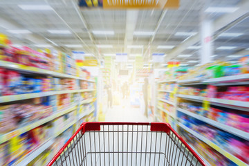 Supermarket aisle with empty red shopping cart