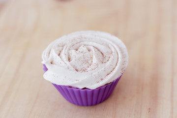 Vanilla cupcake with white frosting and flowers on a table