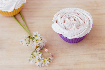 Vanilla cupcake with white frosting and flowers on a table