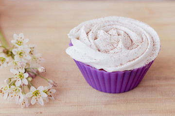 Vanilla cupcake with white frosting and flowers on a table