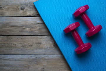 dumbbell and yoga mat on wood table