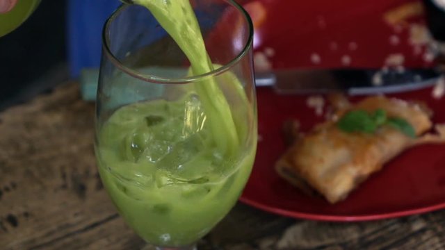 Close up of pouring green juice into glass in cafe, super slow motion 240fps
