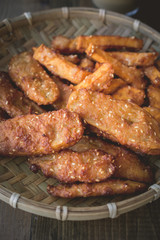 Golden Brown Deep Fried Bananas on threshing basket with wooden