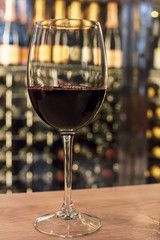 Red wine glass in front of blurred rack