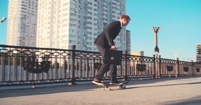  Businessman performing jump on skateboard while riding in city at summer day