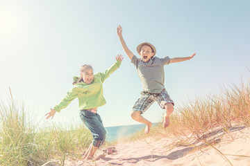 Boy and girl jumping in the dunes at the beach