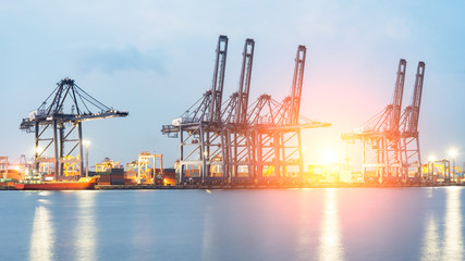 Obraz premium Container Cargo freight ship with working crane bridge in shipyard at dusk for Logistic Import Export background