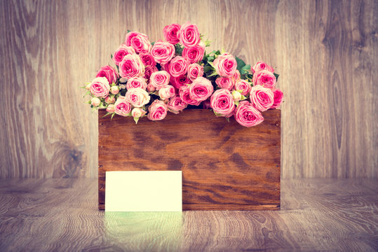 Roses in the box on wooden background. Toned image