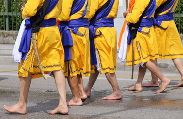 Five men with long dresses walking barefoot through the streets