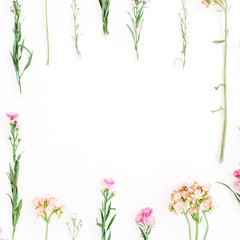 Frame with colorful wildflowers, green leaves, branches on white background. Flat lay, top view. Valentine's background