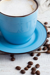 Cappuccino in a blue mug close-up on a white background