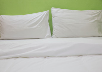 An unmade bed with white linens background green
