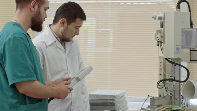 Engineer and his assistant controlling process of making printed circuit board by machine