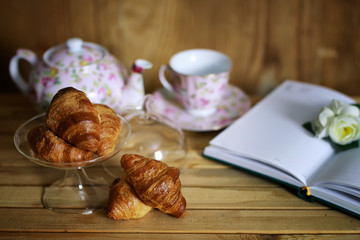cup with tea croissant book