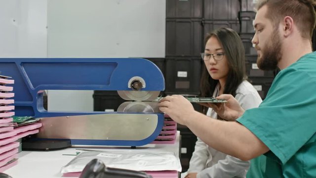 Asian woman helping technician separating PCB material with cutting machine 