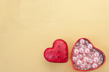 Hearts and box with pink pearls on a yellow background