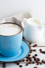 a cup of cappuccino and a milk jug