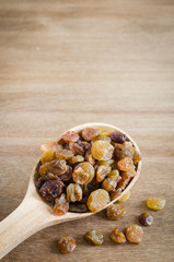 Dried Organic Raisins in a wooden Spoon on Rustic Background.