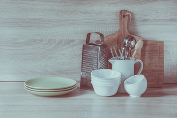 Crockery, tableware, utensils and other different stuff on wooden table-top. Kitchen still life as background for design. Image with copy space. Toned image.