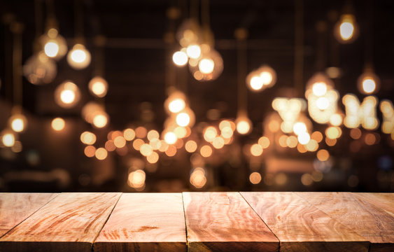 Wood table top on blurred of cafe ( restaurant ) with light gold bokeh