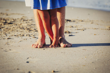 Close up of father and little daughter feet on beach