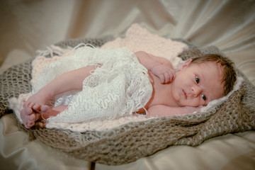 Portrait of a newborn baby infant toddler in bed. Close up top view portrait infant baby. Happy little newborn child girl lying in child bed.Happy smiling little girl.Healthy newborn girl after birth 