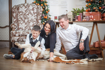 mother, father and little boy with Husky background Christmas tree
