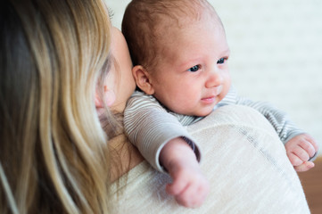 Unrecognizable young mother holding baby son in her arms