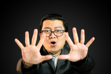 Young Asian businessmen are afraid of something in the dark. He raised his hand to block