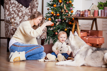 Mom and her children having fun playing together Christmas tree.