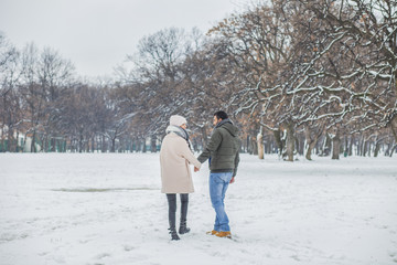 Fototapeta na wymiar Happy loving couple walking in winter park enjoying snow