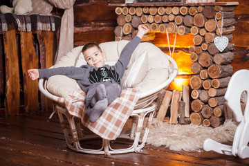 Boy in hat sitting in chair Christmas tree and gifts