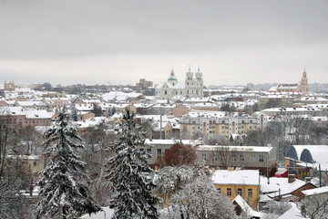 Fototapeta premium Panorama Grodno after a snowfall. Roofs of old houses and a Catholic churches covered with snow in perspective. Belarus winter.