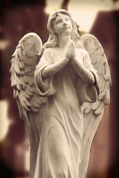 Vintage image of a sad angel on a cemetery against the backgroun