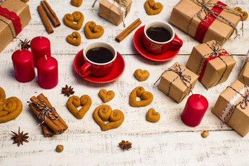 Obraz na płótnie Canvas Two red coffee cups, gifts, cookies in the shape of a heart on a white wooden background