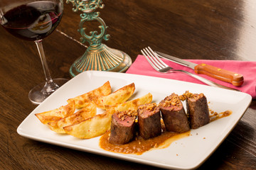 Close up of forest animal steak with potatoes and a glass of win