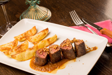 Close up of forest animal steak with potatoes and a glass of win