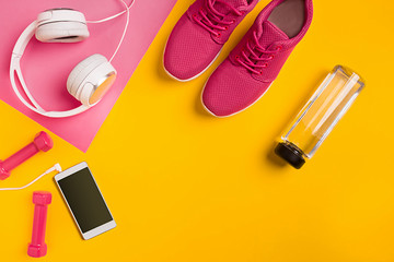 Athlete's set with female clothing, dumbbells and bottle of water on yellow background